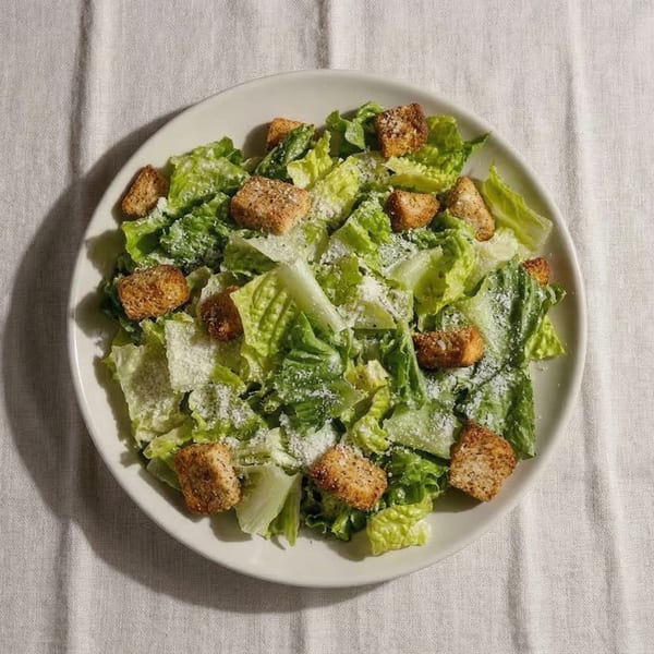 Overhead view of a Caesar salad with romaine lettuce, croutons, and grated Parmesan cheese.