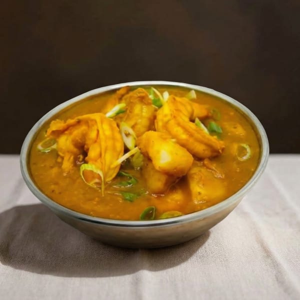 A bowl of yellow curry with chicken and potatoes, garnished with green onions.